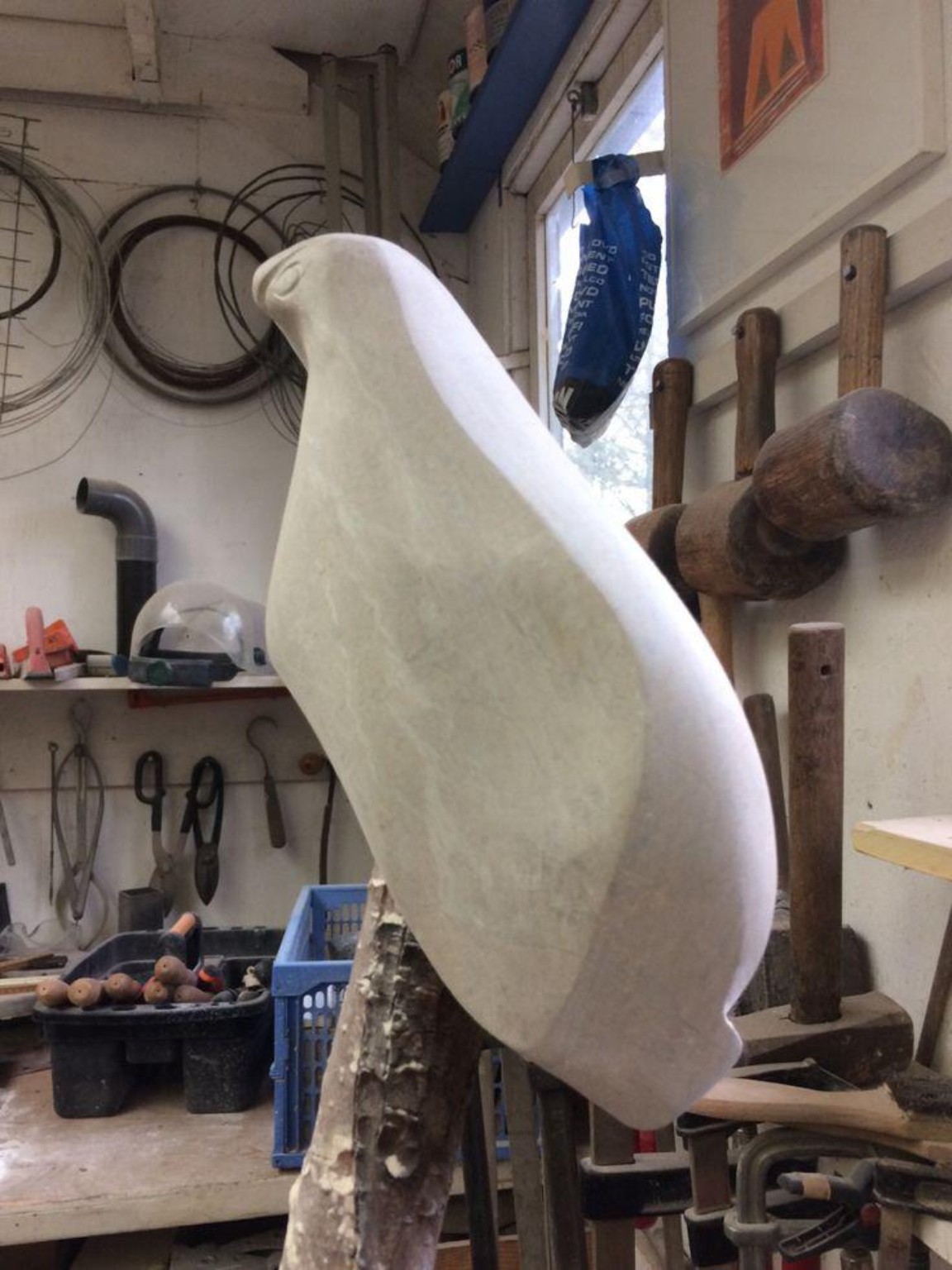 Stenen vogelbeeld op een houten tak in het atelier
